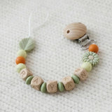 Attache tétine MAM personnalisée en silicone et bois, perles marguerite sauge et feuille, tons vert sauge et rouille, longueur 22 cm sans le clip et la tétine.