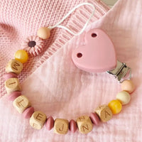 Découvrez notre attache tétine en silicone et bois au couleur rose thé bois et or 