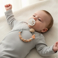 attache tetine clip silicone gris et peche porter par un bébé