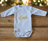 Body blanc pour bébé en coton avec prénom personnalisé en bleu marine, modèle à manches longues avec ouverture croisée.