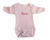 Body de naissance rose pour bébé fille avec finitions délicates posé à plat.