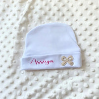 poser à plat sur une couverture un bonnet bébé fille avec noeud brodé or personnalisé 