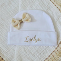 ce bonnet bébé naissance en coton blanc poser a plat son noeud paillette crème 