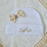 ce bonnet bébé naissance en coton blanc poser a plat son noeud paillette crème 