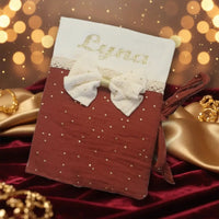 Photo d'un protège carnet de santé en gaze de coton terracotta avec flocage prénom pailleté et détail d'un nœud chic au style bohème.