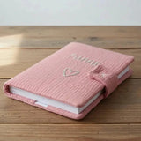 protège carnet de santé de couleur frammboise poser sur une table 