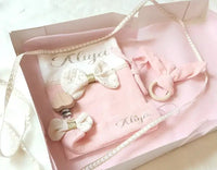 présentation d'un coffret cadeau naissance personnalisée de couleur rose avec une attache tétine une housse de carnet de santé un anneau de dentition et une boite cadeau personnalisée