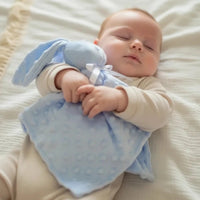 doudou sans yeux bleu clair minky personnalisé dans les bras de bebe