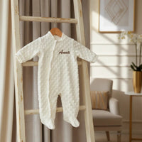 grenouillère bébé de couleur crème accrocher sur un ceintre et suspendue sur une échelle en bois 