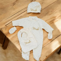 grenouillère bébé poser sur une table avec son bonnet ses moufles son bonnet assortis et personnalisé