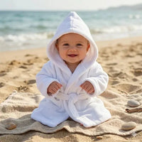 peignoir bebe 2 ans porter par un bébé assis sur le sable avec un fond de place