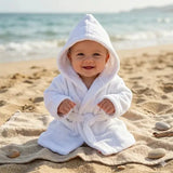 peignoir bebe 2 ans porter par un bébé assis sur le sable avec un fond de place