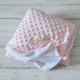 poser sur un fond de bois blanc un plaid bebe polaire de couleur rose personnalisé 