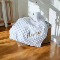 posé sur un coffret un plaid polaire bebe de couleur blanche en minky personnalisé