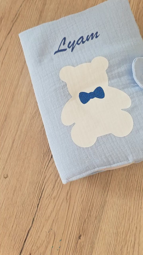 Vidéo de présentation d'un protège carnet de santé personnalisé en gaze de coton bleu avec motif petit ours, montrant les détails du tissu molletonné et le prénom floqué