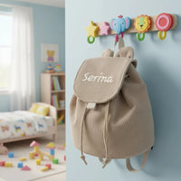 sac a dos maternelle personnalisable avec le prénom de l'enfant accroché par une patère 